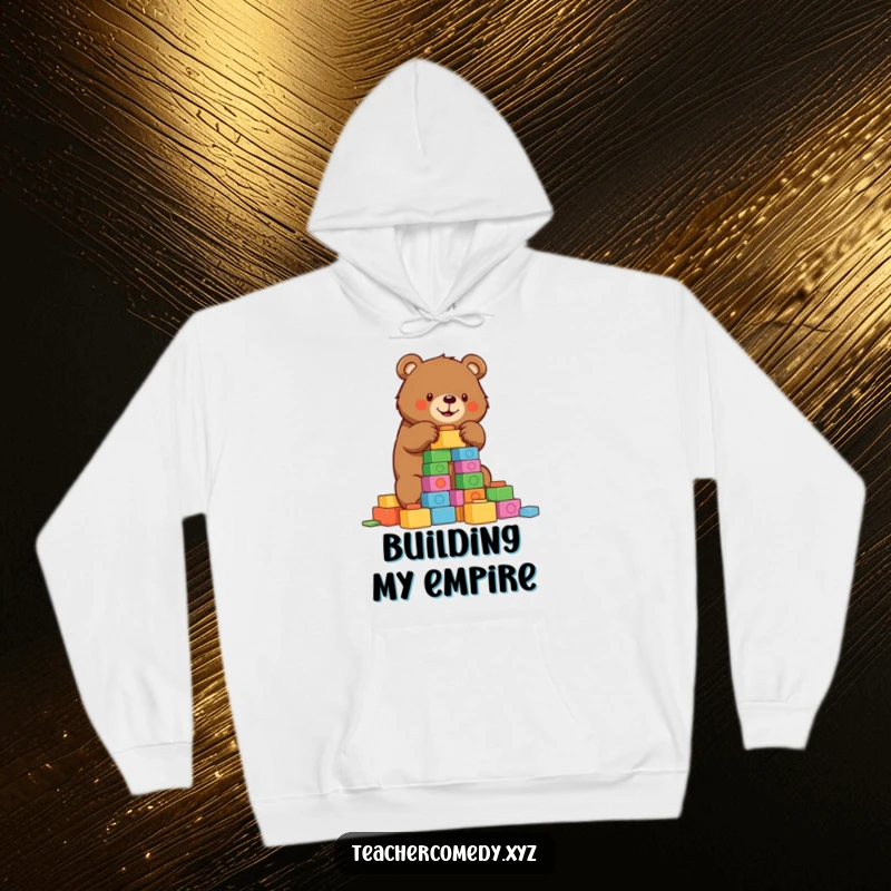 Funny bear hoodie depicting a determined bear constructing a tower of colorful building blocks, perfect for cozy building sessions.